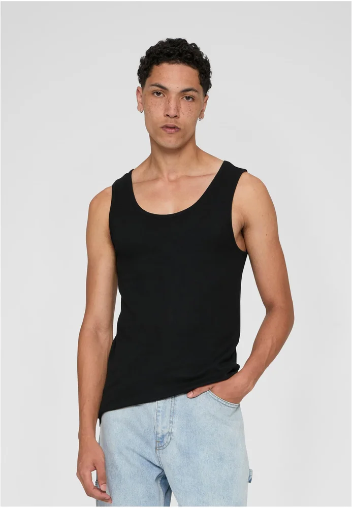 Das "2-Pack Seamless Tanktop" ist ein schwarzes, ärmelloses Tanktop aus 100 % Baumwolle, das eine nahtlose Passform bietet. Der Mann trägt das Tanktop zusammen mit blauen Jeans und steht in einer lässigen Pose vor einem neutralen Hintergrund.